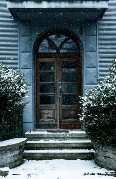 Stone decor around wooden door for front door ideas in 2023 blog. Photo by Mariana Kurnyk: https://www.pexels.com/photo/closed-brown-wooden-door-1779250/